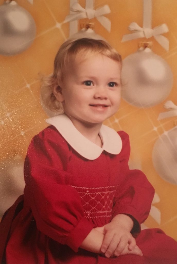 Younger Michelle at the age of two in a red dress
